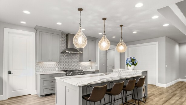 Une cuisine moderne dotée d’un grand îlot central, de luminaires suspendus et d’un pare-feu hexagonal.