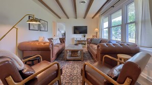A living room with brown leather sofas, a wooden coffee table, a TV, and large windows. - New! Sleeps 16! Across from Sight&Sound! Location! (Ronks)