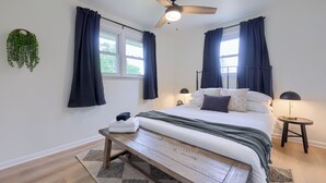 A bedroom with a bed, a ceiling fan, a bedside table with a lamp, and a window with curtains. - New! Sleeps 16! Across from Sight&Sound! Location! (Ronks)