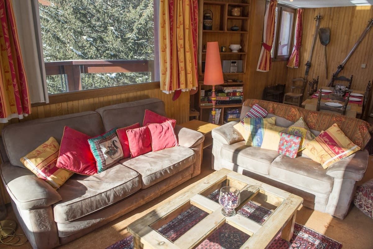 A cozy living room with two sofas, a coffee table, and a bookshelf.