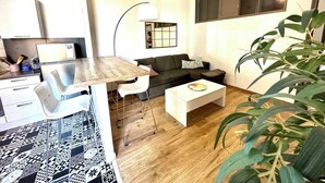 Et moderne opholdsrum med et køkkenområde, et spisebord, en sofa og et sofabord.