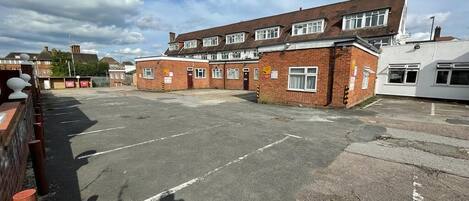 A parking lot with a row of terraced houses in the background.