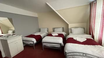 A room with three beds, a desk, and a mirror.