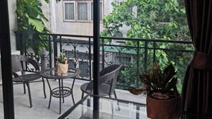 A balcony with a glass table and chairs, surrounded by potted plants and a view of a residential area. - Noc House (Bangkok)