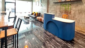 A modern interior with a reception desk, seating area, and a large window. - Noc House (Bangkok)