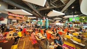 A busy indoor dining area with multiple tables and chairs, high ceilings with exposed beams, and large pendant lights. - Noc House (Bangkok)