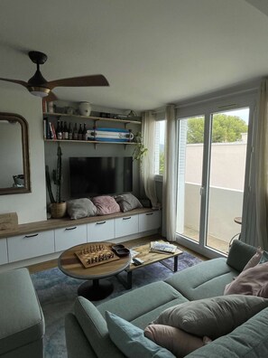 Ein Wohnzimmer mit einer Couch, einem Couchtisch, einem Fernseher und einem Bücherregal.