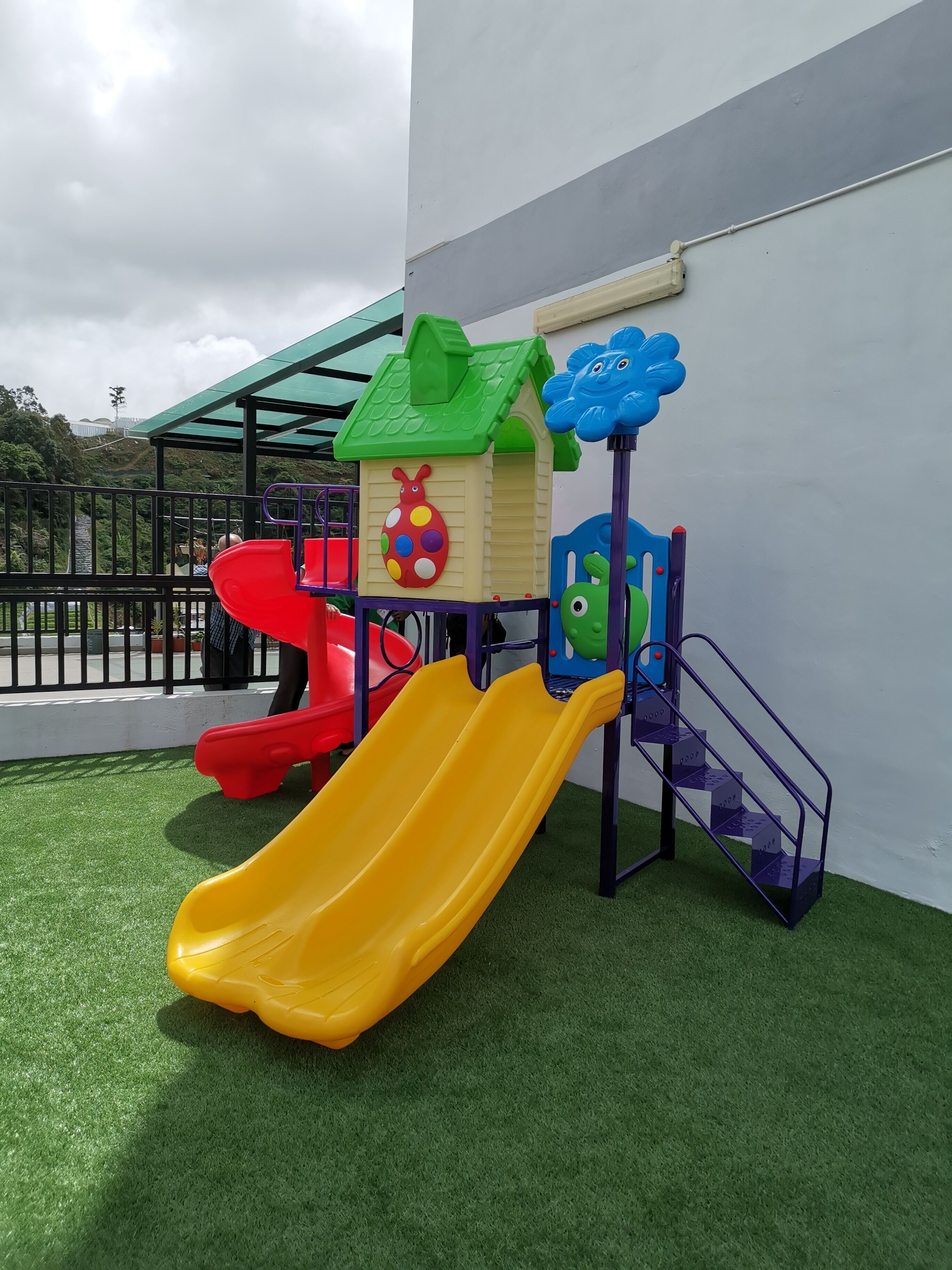 Un parque infantil con un tobogán amarillo, un tobogán rojo y una estructura para escalar.