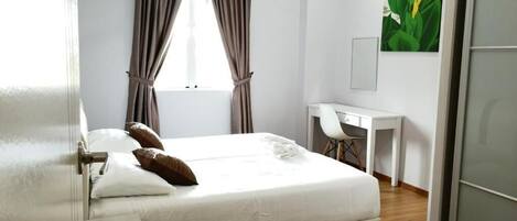 A bedroom with a bed, a desk, and a chair.