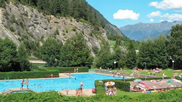 A swimming pool surrounded by lush greenery and mountains in the background. - Sonnenschein B by Interhome (Spiss-Samnaun)