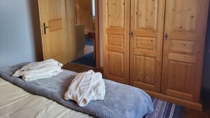 A bedroom with a bed, two towels, wooden wardrobes, and a hallway leading to another room. - Sonnenschein B by Interhome (Spiss-Samnaun)