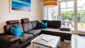 A modern living room with a sectional sofa, a coffee table, and a large window with a view of greenery. - MeerZeit I by Interhome (Burhave)