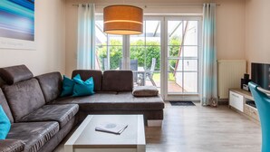 A modern living room with a brown leather sofa, a white coffee table, and a large window with curtains. - MeerZeit I by Interhome (Burhave)