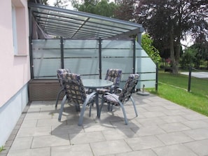 A covered patio with a table and four chairs.