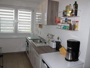 Una cocina moderna con lavavajillas incorporado, cafetera y estante con varios utensilios de cocina.