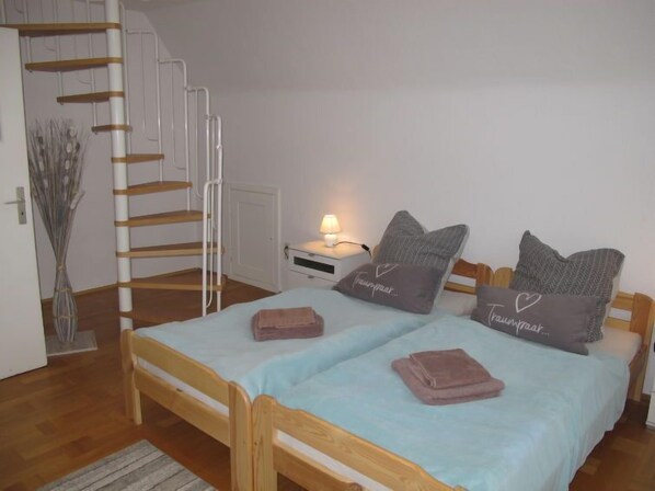 A bedroom with a wooden bed, two pillows, a bedside table with a lamp, and a staircase.