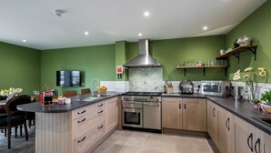 Una cocina moderna con una isla central, electrodomésticos de acero inoxidable y paredes verdes.
