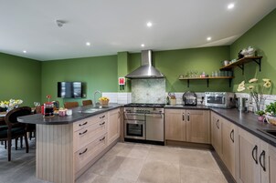Una cocina moderna con una isla central, electrodomésticos de acero inoxidable y paredes verdes.