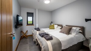 Habitación de hotel con dos camas, televisión, ventana y puerta.