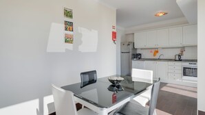 Una cocina moderna con armarios blancos, un refrigerador de acero inoxidable y una cafetera.
