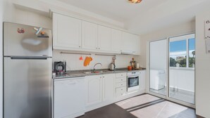 Una cocina moderna con armarios blancos, electrodomésticos de acero inoxidable y un amplio ventanal con vistas al exterior.