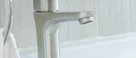 A modern bathroom with a white sink and a chrome faucet.