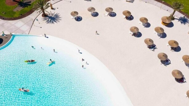 An aerial view of a resort with a large swimming pool, sun loungers, and palm trees. - Joya Vacation Club (Vítor)