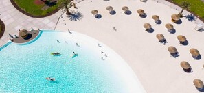 An aerial view of a resort with a large swimming pool, sun loungers, and palm trees. - Joya Vacation Club (Vítor)