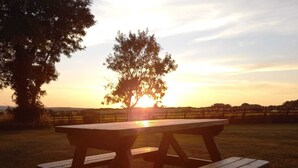 A picnic table in a grassy field with a sunset in the background. - The Pod Garden- Cozy Glamping Pod, Rural Location (Newquay)