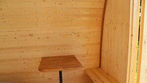 A small wooden room with a single table and bench. - The Pod Garden- Cozy Glamping Pod, Rural Location (Newquay)