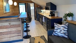 Une cuisine moderne avec un coin bar, des murs en bois et un espace détente avec un canapé et une plante.