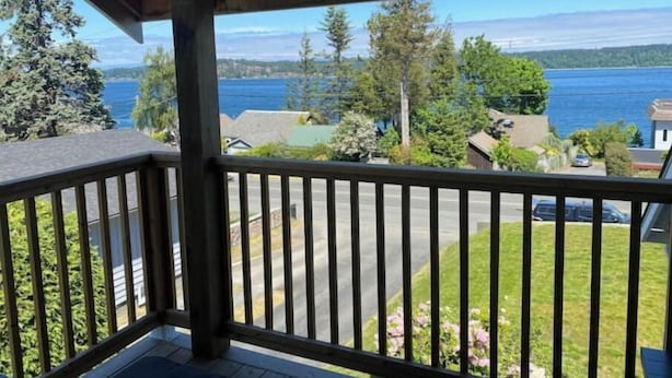 Un balcon en bois offrant une vue sur un quartier résidentiel et un plan d’eau.