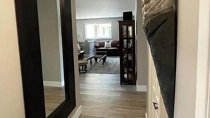 A hallway with a large mirror, a dark-framed door, and a wall-mounted shelf with a decorative item. - Lake House Barry's Bay (Barry's Bay)