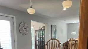 A kitchen with wooden cabinets, a black countertop, and two pendant lights. - Lake House Barry's Bay (Barry's Bay)