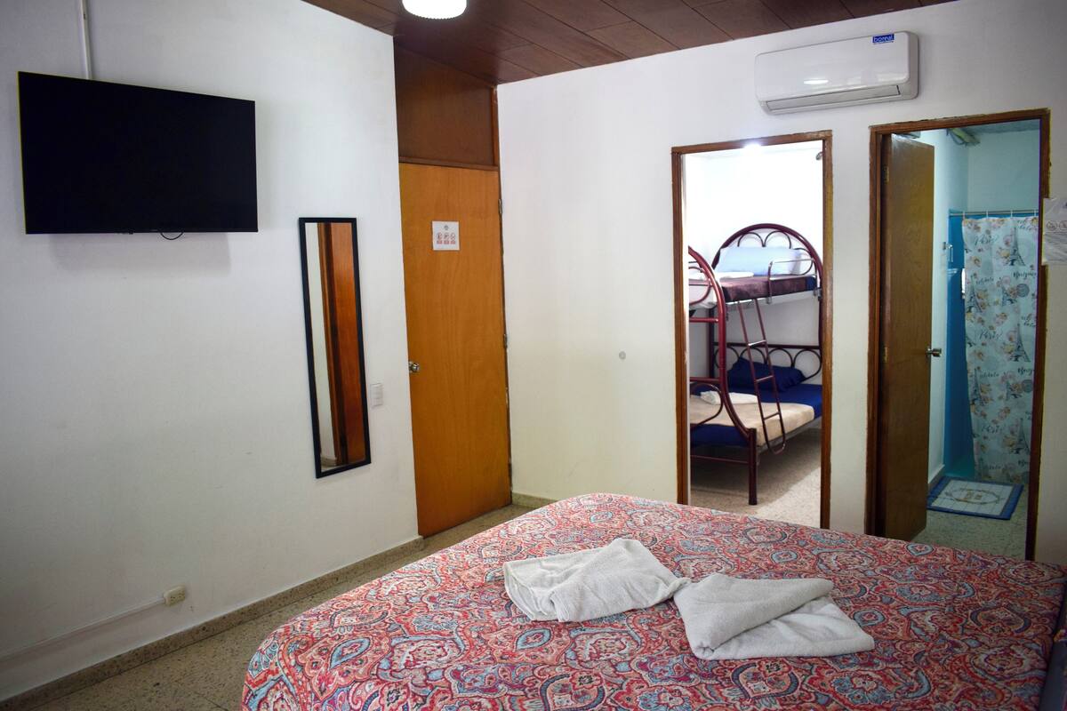 Een slaapkamer met een bed, een televisie, een kledingkast en een spiegel.