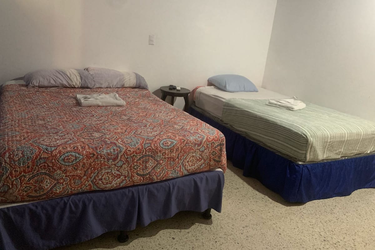 Een kamer met twee bedden, waarvan één groter en één kleiner, beide met beddengoed met een patroon.