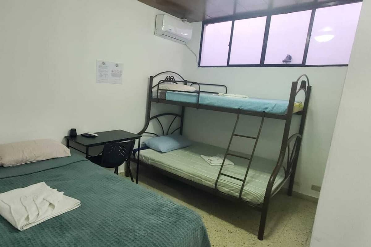 Een studentenkamer met stapelbedden, een bureau, een stoel en een raam.