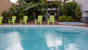 Piscina com quatro cadeiras verdes e uma pequena banheira de hidromassagem.