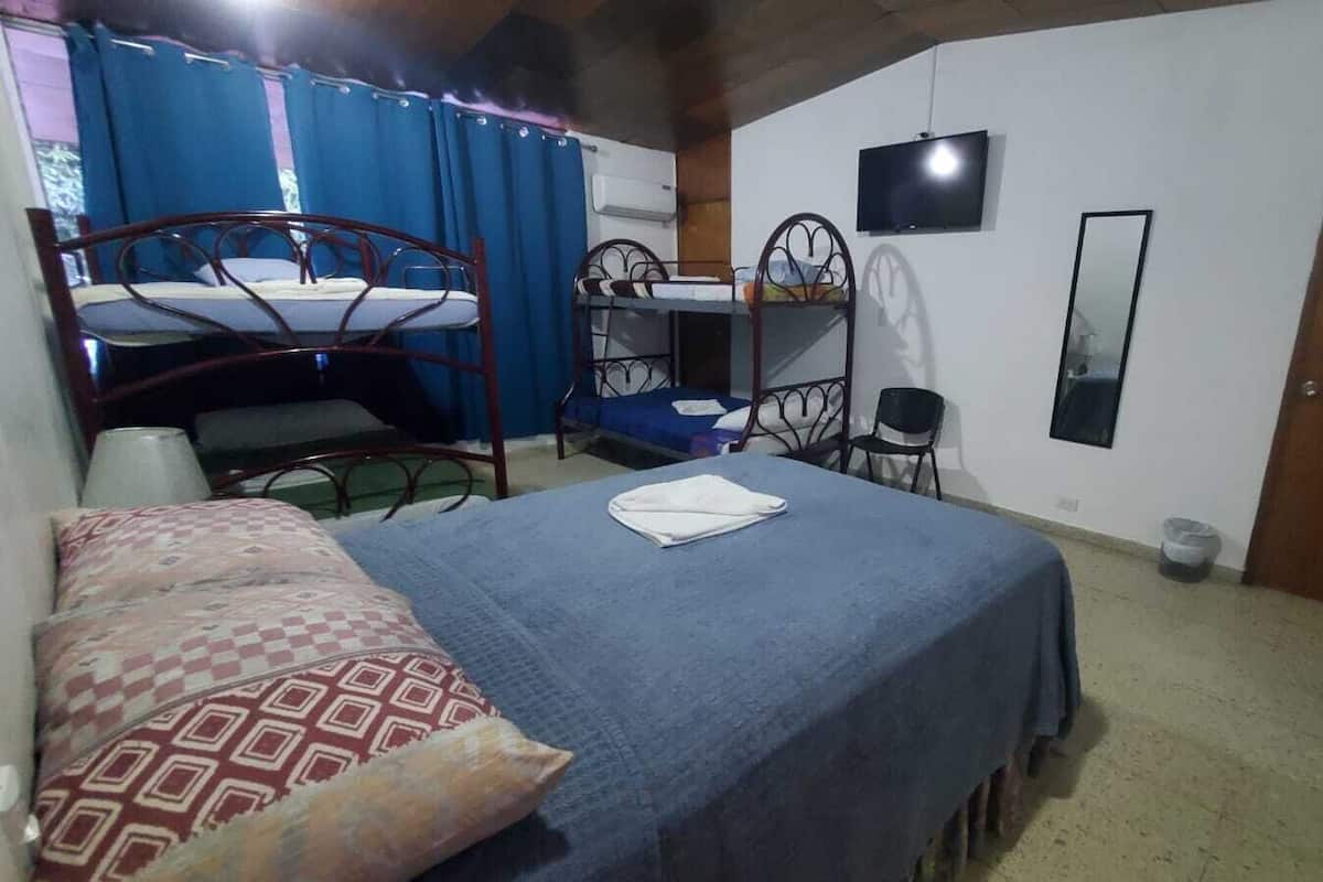 Een kamer met stapelbedden, een televisie, een spiegel en een bed met een gestreept kussen.