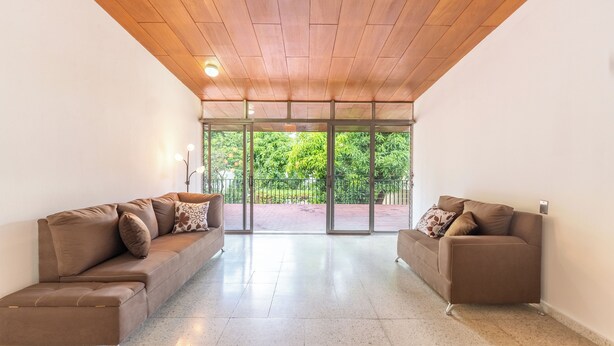 Uma sala de estar ampla com dois sofás marrons e teto de madeira.