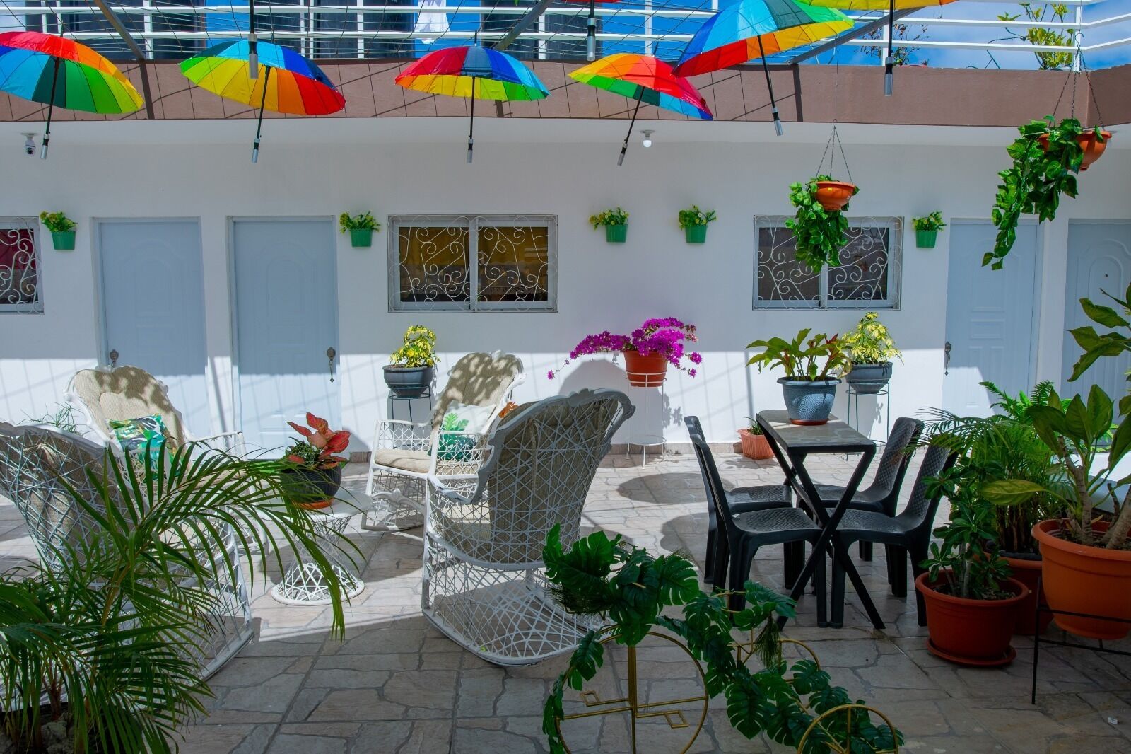 A patio area with outdoor seating, potted plants, and hanging umbrellas.