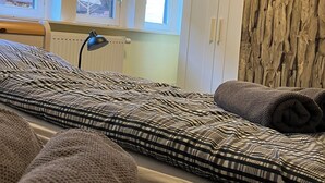 A room with a bed, a radiator, a window, and a wooden wall. - Small, fine vacation apartment in the heart of Fürstenau (Fürstenau)