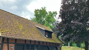 A traditional building with a tiled roof, brick walls, and a wooden bench outside. - Small, fine vacation apartment in the heart of Fürstenau (Fürstenau)