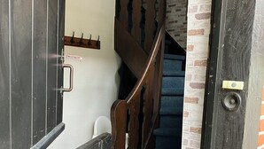 A staircase with wooden railings and a blue carpet, leading to a room with a white wall and a hanging light fixture. - Small, fine vacation apartment in the heart of Fürstenau (Fürstenau)