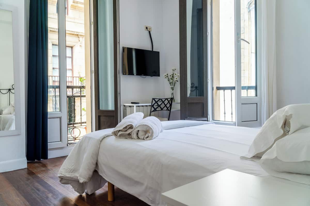 A hotel room with a large bed, a TV mounted on the wall, a small table, and a chair.