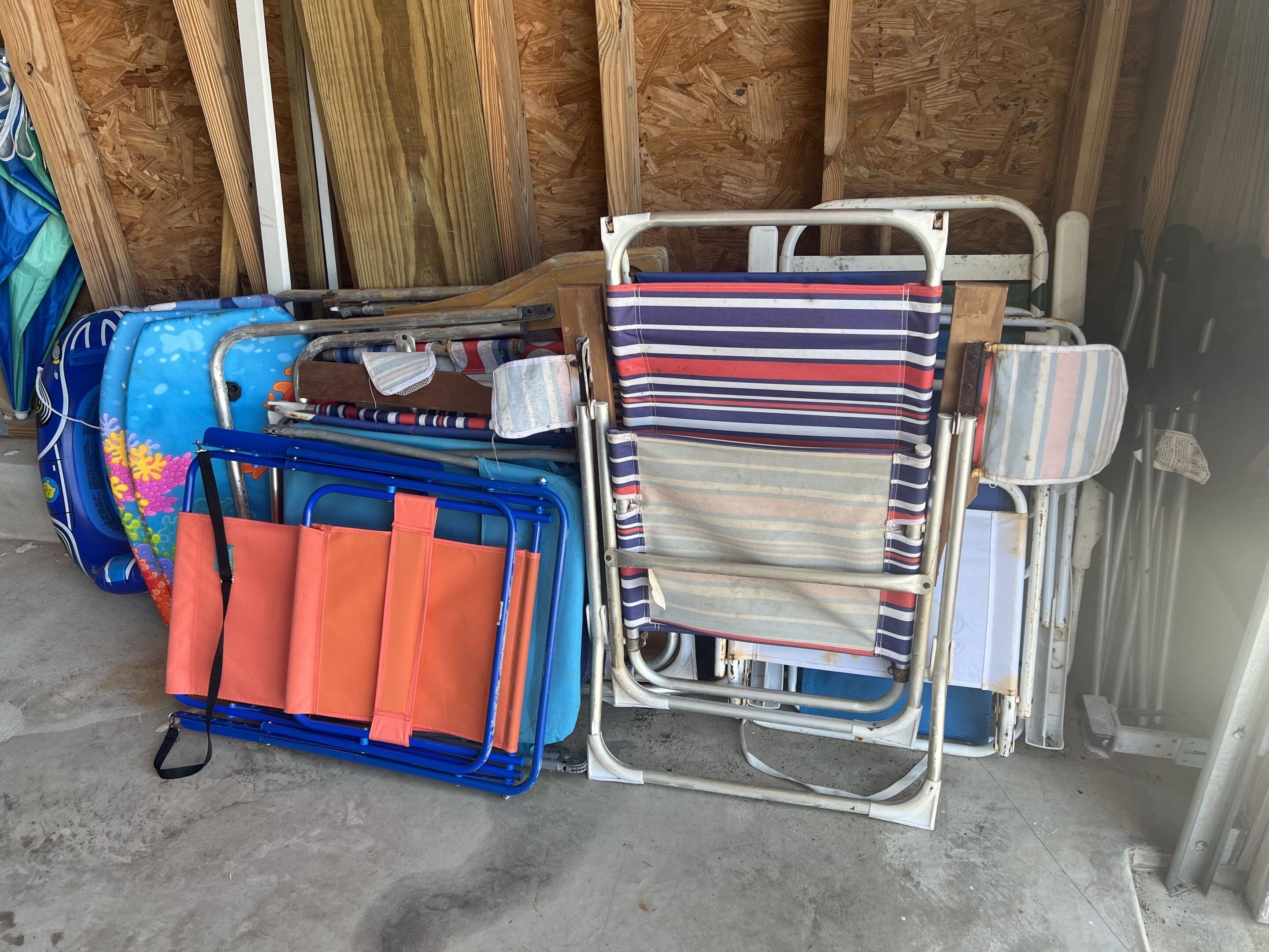 A storage area with various items including a blue and orange chair, a striped cushion, and a metal frame.