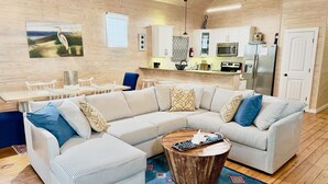Ein modernes Wohnzimmer mit einer Eckcouch, einem Couchtisch und einer Küchenzeile im Hintergrund.