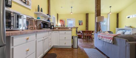 A compact kitchen with white cabinets, a microwave, and a coffee maker.