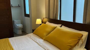 Une chambre d’hôtel avec un lit, une table de chevet, une fenêtre et une vue sur l’extérieur.