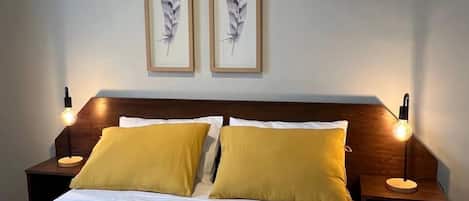 A hotel room with a large bed, two nightstands, and two wall-mounted lamps.